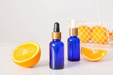 Temel yağ şişeleri ve açık arkaplanda taze portakal