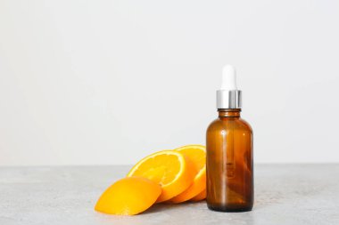 Temel yağ şişesi ve hafif arkaplanda taze portakallar