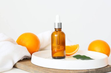 Temel yağ şişesi ve hafif arkaplanda taze portakallar