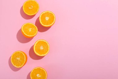 Pembe arkaplanda taze kesilmiş portakallar