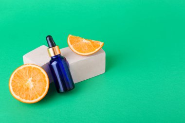 Yeşil arka planda bir şişe gerekli yağ ve taze kesilmiş turuncu.