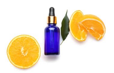 Beyaz arka planda bir şişe gerekli yağ ve taze kesilmiş turuncu.