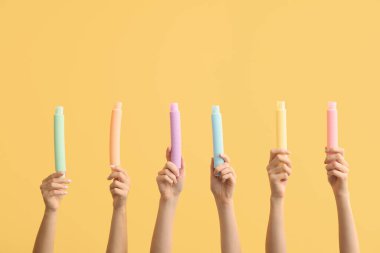 Renkli arka planda popüler pop tüpleri olan eller