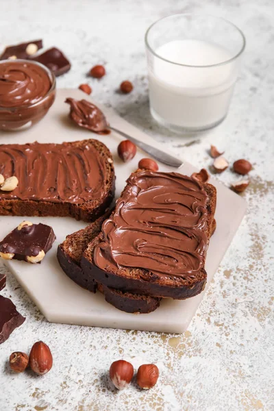 Çikolata ezmeli ekmek, fındık ve arka planda bir bardak süt.