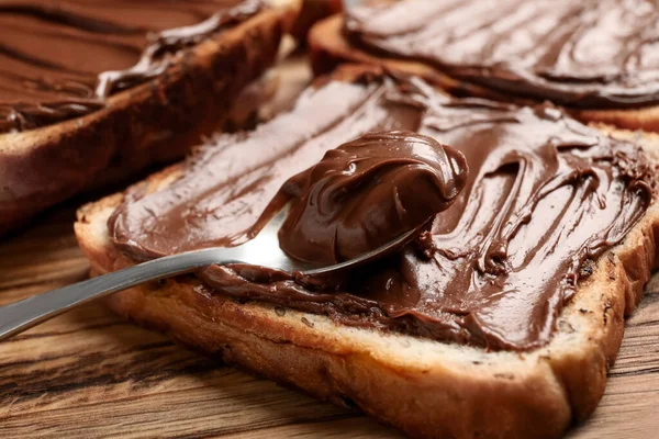 Tahta tahta tahtada çikolata ezmesi ve fındık, yakın plan.