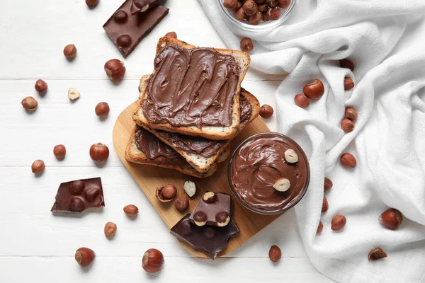 Brot Mit Schokoladenpaste Und Haselnüssen Auf Weißem Holzgrund — Stockfoto