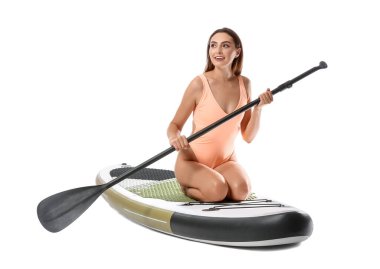 Sörf tahtası olan ve beyaz arka planda kürek çeken güzel bir genç kadın.