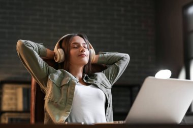 Bilgisayarlı, müzik dinleyen ve akşamları evde dinlenen genç ve güzel bir kadın.