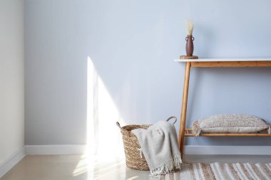 Vazolu masa, yastık ve sepet, ışık duvarının yanında.