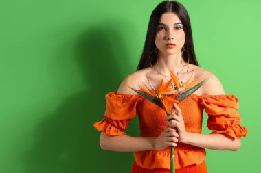 Renkli arkaplanda strelitzia çiçekleri olan güzel bir kadın.
