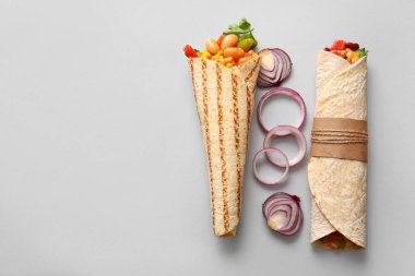 Gri arka planda lezzetli dürümler ve soğan.