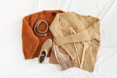 Şık kadın kazakları, askılar, kemer ve ayakkabılar hafif buruşuk kumaş arka planda