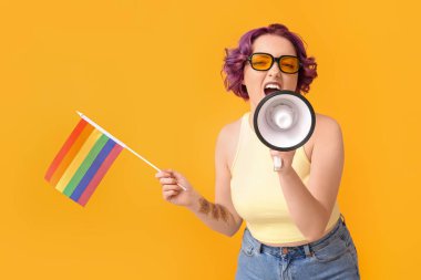 Sarı arka planda LGBT bayrağı ve megafonu olan genç bir kadın.