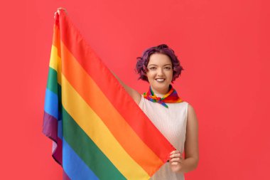 Kırmızı arka planda LGBT bayrağı olan genç bir kadın.
