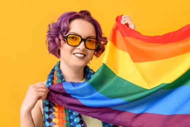 Sarı arka planda LGBT bayrağı olan genç bir kadın.
