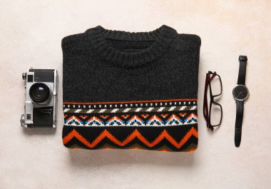Erkek süveter, fotoğraf makinesi, gözlük ve hafif arka planda kol saati.