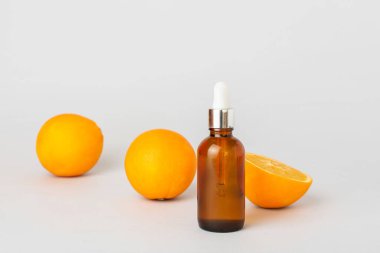 Temel yağ şişesi ve hafif arkaplanda taze portakallar