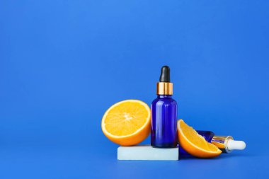 Mavi arka planda gerekli yağ ve taze portakal şişeleri