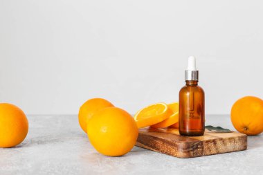Temel yağ şişesi ve hafif arkaplanda taze portakallar