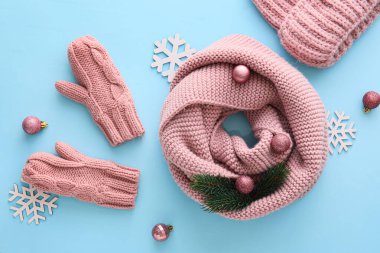 Örgü şapka, atkı, eldiven ve mavi arka planda Noel dekoru olan güzel bir kompozisyon.