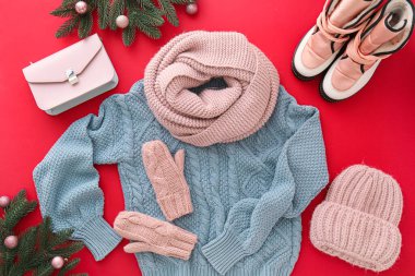 Kırmızı arka planda şık kışlık giysiler, aksesuarlar, ayakkabılar ve Noel dekoru