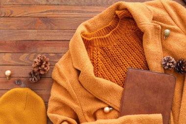 Kış giysileri, çanta ve Noel dekoru ahşap arka planda.