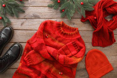 Şık kışlık giysiler, ayakkabılar ve ahşap arka planda Noel dekoru.