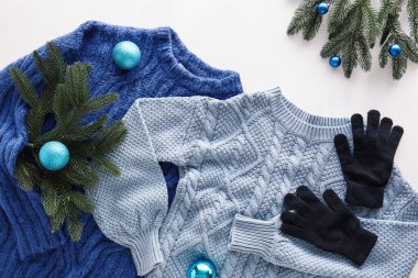 Açık arkaplanda örülmüş süveterler, eldivenler ve Noel dekoru.