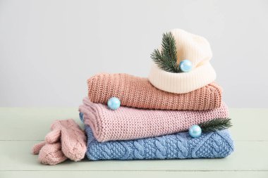 Örgü süveterler, şapka, eldivenler ve açık arkaplanlı ahşap masa üzerindeki Noel dekoru