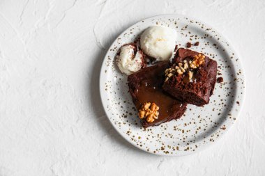 Lezzetli çikolatalı browni ve beyaz arka planda dondurmayla dolu bir tabak.