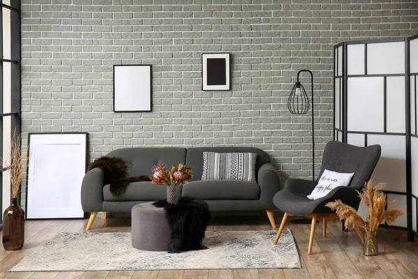 レンガの壁の背景にグレーのソファとスタイリッシュなインテリア — ストック写真
