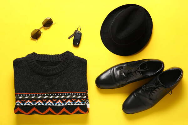 Male sweater, felt hat, shoes, sunglasses and car key on yellow background