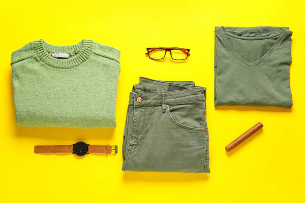 Male clothes, wristwatch, eyeglasses and cigar on yellow background