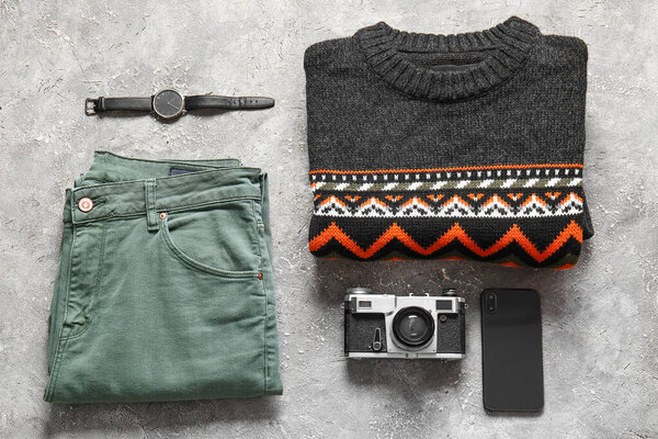 Male sweater, pants, wristwatch, photo camera and mobile phone on grunge background