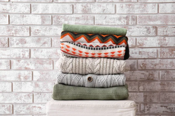 Stack Stylish Sweaters Pouf Light Brick Background — Fotografia de Stock