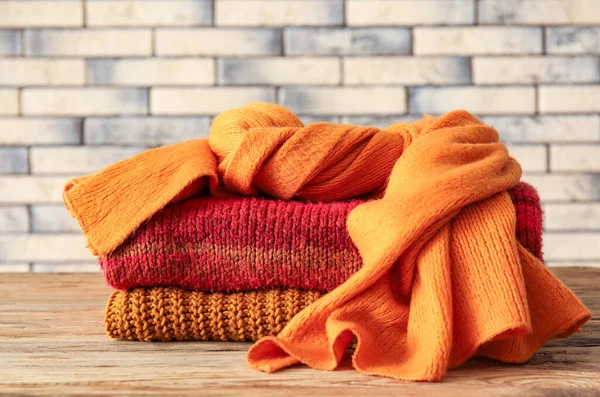 Knitted Sweaters Scarf Wooden Table Brick Wall Background — Stock Photo, Image