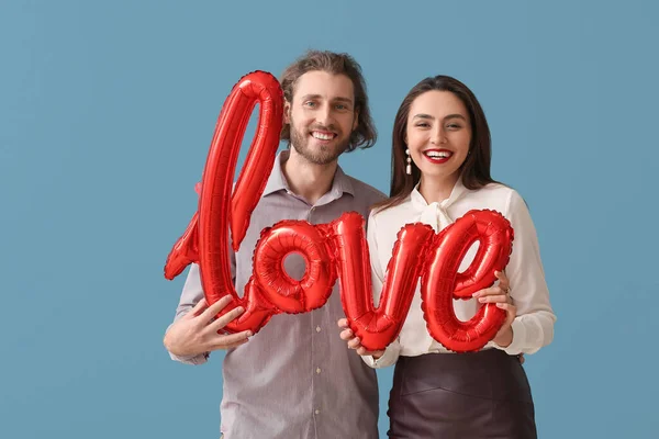 一对快乐的年轻夫妇 有着蓝色背景的气球形状的文字爱情 情人节庆祝活动 — 图库照片
