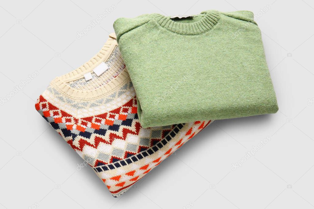 Different stylish sweaters on grey background