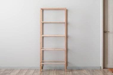 Boş ahşap raf ünitesi ışık duvarının yanında.