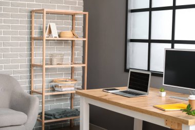 Odasında tuğla duvar olan ahşap raf ünitesi.