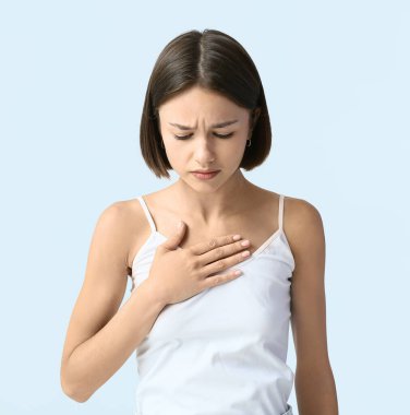 Genç bir kadın arka planda göğsünde rahatsızlık hissediyor. Kanser farkındalığı kavramı