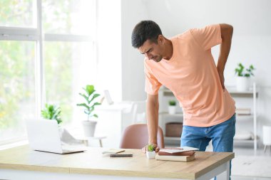 Genç adam evde sırt ağrısı çekiyor.