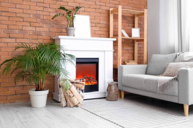 Modern oturma odasının içinde şömine rafı, odun ve kanepe var.