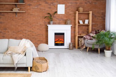 Modern oturma odasının içinde şömine rafı, odun ve kanepe var.