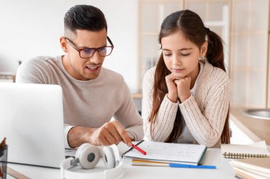 Küçük kız evde öğretmeniyle ders çalışıyor.