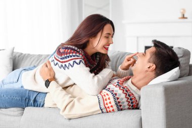 Mutlu genç çift evde kalın kazaklar giyiyor.