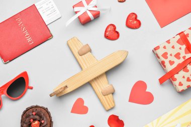 Ahşap uçak, hediye kutuları, güneş gözlükleri ve arka planda kalplerle Sevgililer Günü için güzel bir kompozisyon.