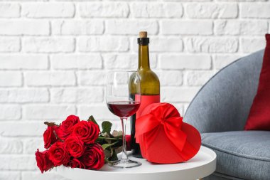 Sevgililer Günü hediyesi, çiçekler ve şarap masada.