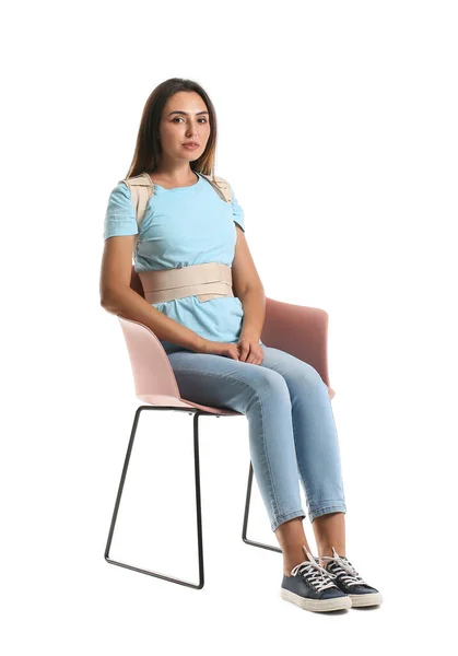 Young Woman Back Brace Sitting Chair White Background — стоковое фото
