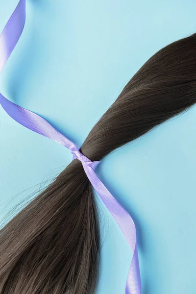 Brunette Hair Strand Donation Lilac Ribbon Blue Background Closeup — Stock Fotó